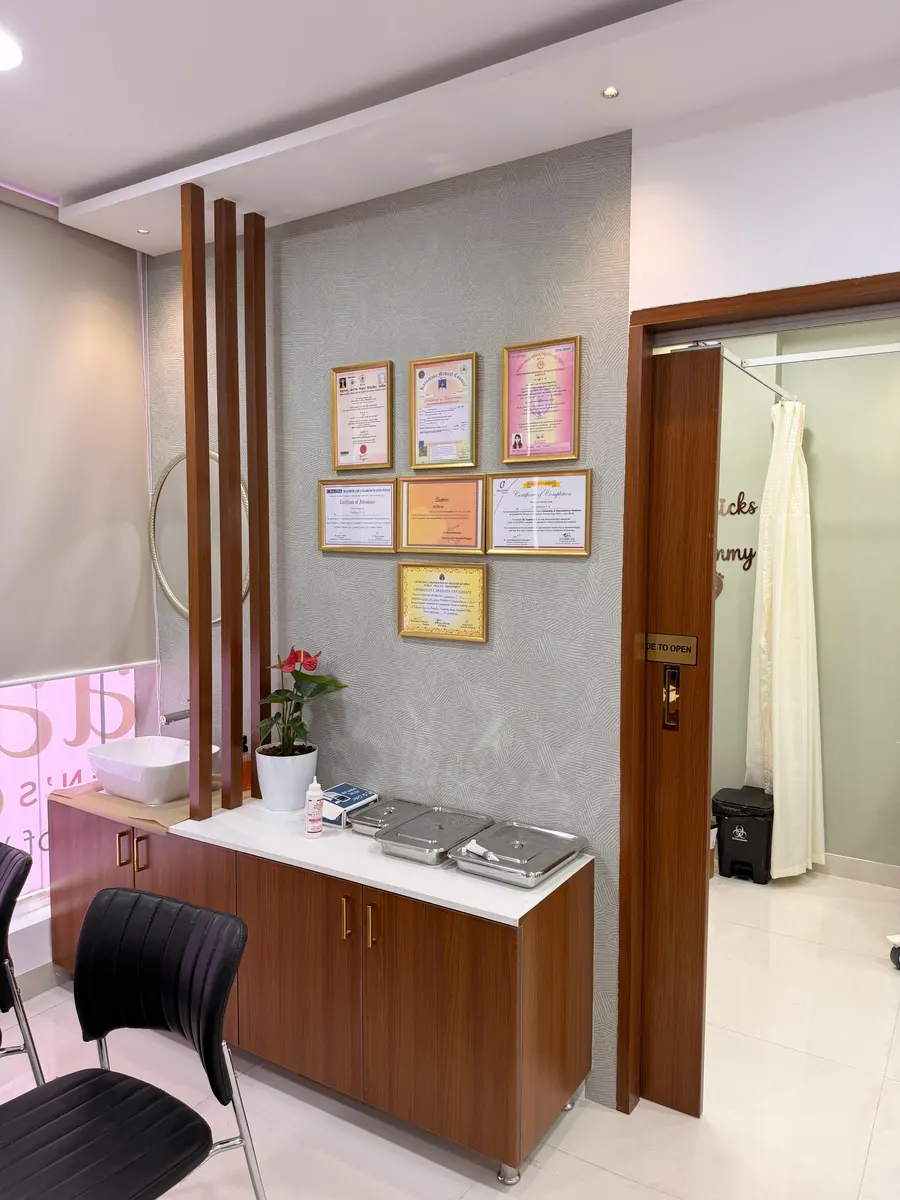 A handwash basin and instrument counter below a wall of framed certificates